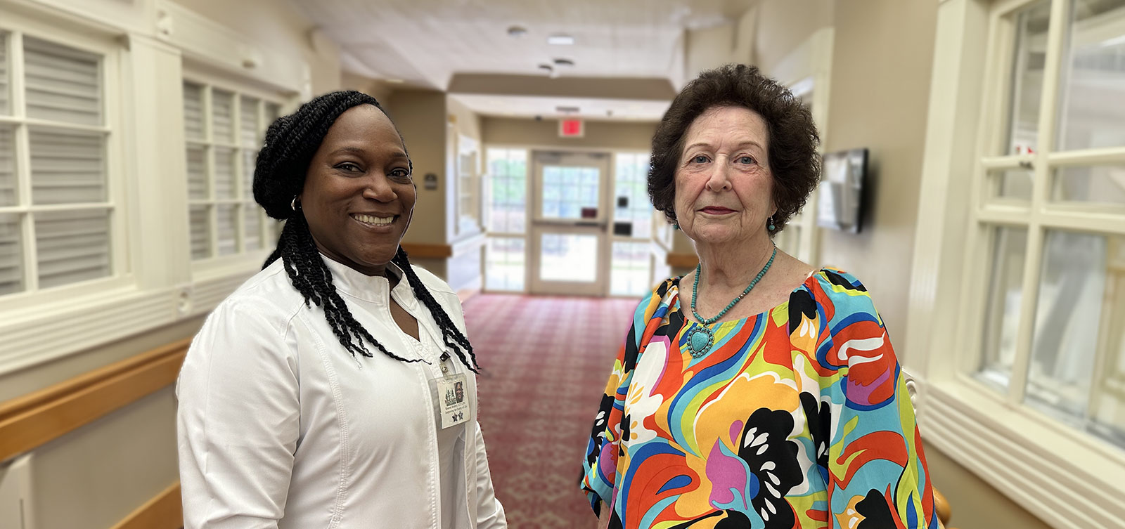 Nurse and older woman smiling in hallway